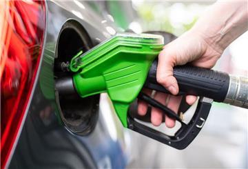 Ein Mann hält an einer Tankstelle an einer Zapfsäule eine Zapfpistole in der Hand und betankt ein Auto. Die beste Zeit zum Tanken hat sich mittlerweile geändert.