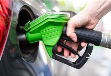 Eine Frau hält an einer Tankstelle eine Zapfpistole in der Hand und betankt ein Auto. Der beste Zeitpunkt zum Tanken hat sich geändert.