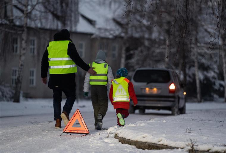 Schnee auf Straße Menschen tragen Warnwesten