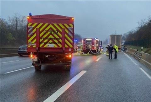Auf der Autobahn A7 steht ein Lkw, der gebrannt hat. Davor steht ein Einsatzfahrzeug der Feuerwehr Bremerhaven.