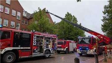 Mehrere Fahrzeuge der Feuerwehr stehen während eines Einsatzes vor einem Gebäude. 