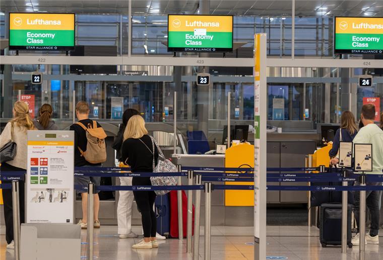 Passagiere stehen an einem Check-in-Schalter der Lufthansa.