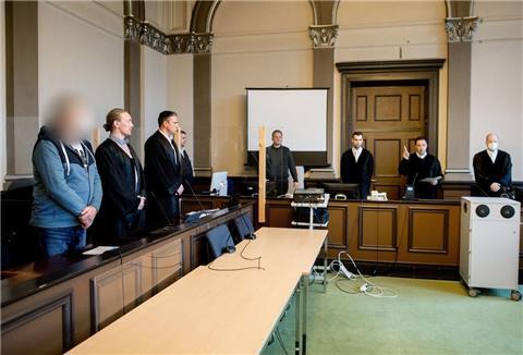 Ein wegen zweifachen Mordes und versuchten Mordes angeklagter Mann steht kurz vor Prozessfortsetzung in einem Gerichtssaal im Landgericht Verden neben seinen Verteidigern Jan Raschka (2.v.l.) und Jakob Struif.