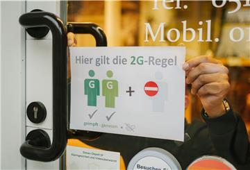 Ein Friseur hängt in seinem Schaufenster ein Schild auf, das auf die 2G-plus-Regel hinweisen soll. 