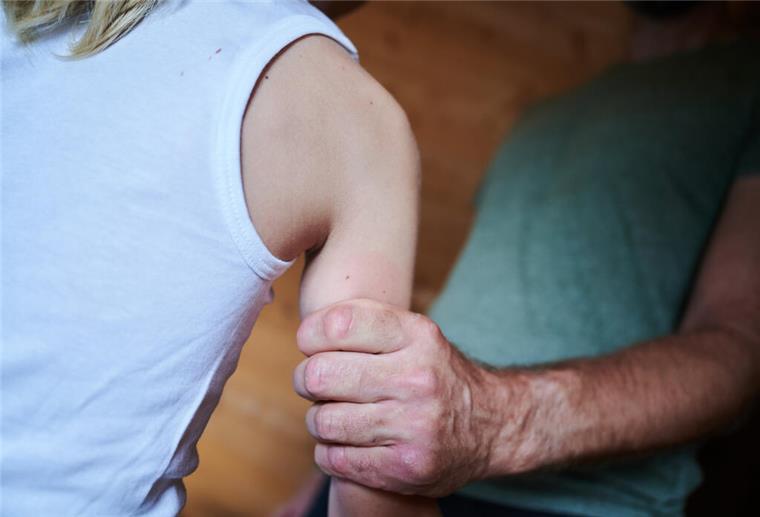 Ein Mann hält ein Kind fest am Arm (gestellte Szene)