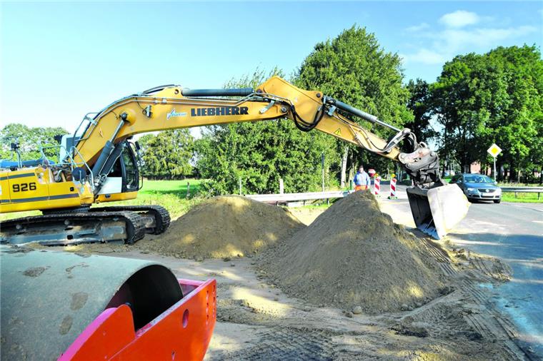 Es geht los: Radweg zwischen Flögeln und Bad Bederkesa wird gebaut Weit fährt Torsten Kugele den Arm seines Baggers aus, um Sand aufzuladen, der zur Bodenverdichtung am Fickmühlener Randkanal verwendet wird. Kollege Jascha Grotheer hat die Warnbaken an der K18 postiert. Sie weisen die Verkehrsteilnehmer auf die Arbeiten für den Radweg hin.