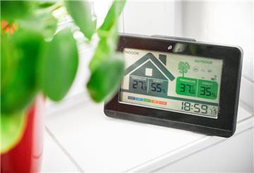 Eine Wetterstation auf der Fensterbank zeigt hohe Temperaturen in der Wohnung und draußen an