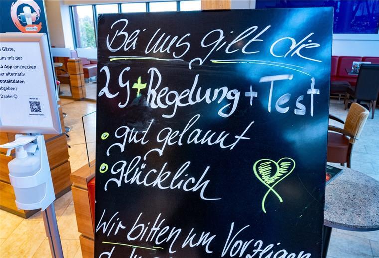 Ein Schild mit dem Schriftzug "2G+Regelung+Test - gut gelaunt - glücklich" steht vor einem Eiscafé