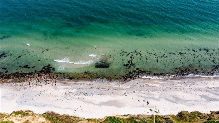 Wellen laufen am Strand der Ostsee am sogenannten Schwedeneck auf den Sand.