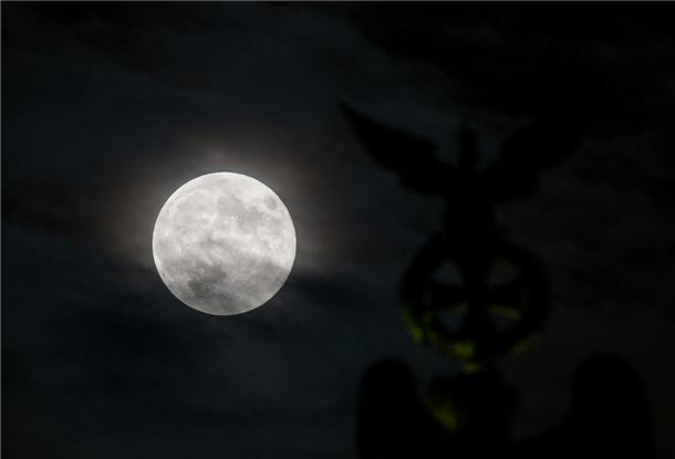 Ein besonders groß erscheinender Vollmond, auch Supermond genannt, ist bei leichter Bewölkung neben der Spitze der Quadriga auf dem Brandenburger Tor zu sehen.