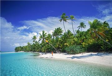 Eine Frau geht am Sandstrand von Aitutaki entlang, einer der Cook Inseln.