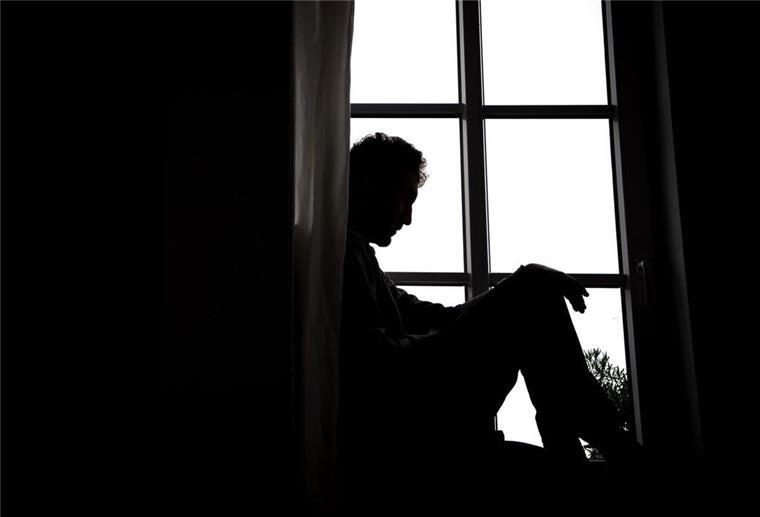 Ein Mann sitzt vor einem Fenster.