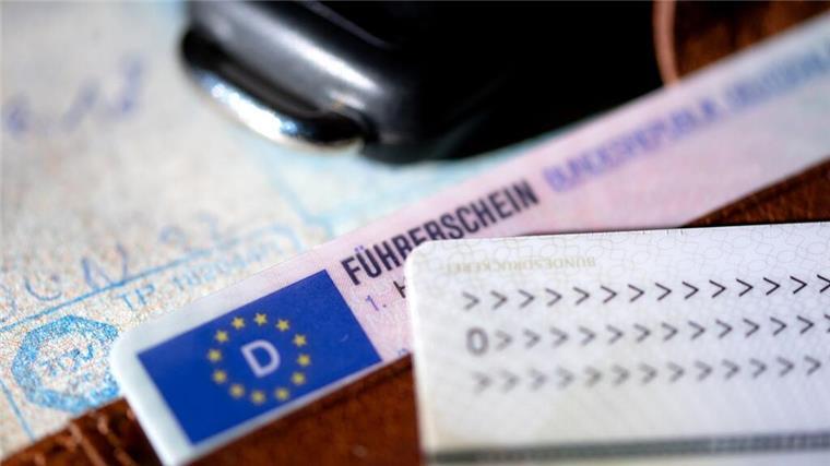 Ein Führerschein, ein Autoschlüssel, ein Personalausweis und eine Zulassungsbescheinigung liegen auf einem Portemonnaie.