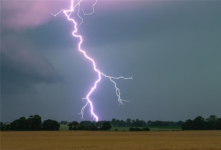 Ein Blitz leuchtet über einer Landschaft auf