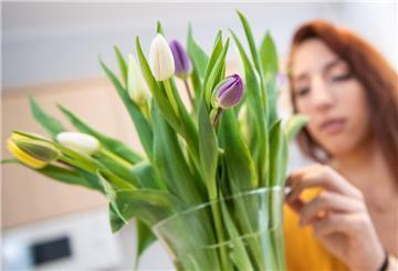 Eine Frau betrachtet einen Tulpenstrauß. 