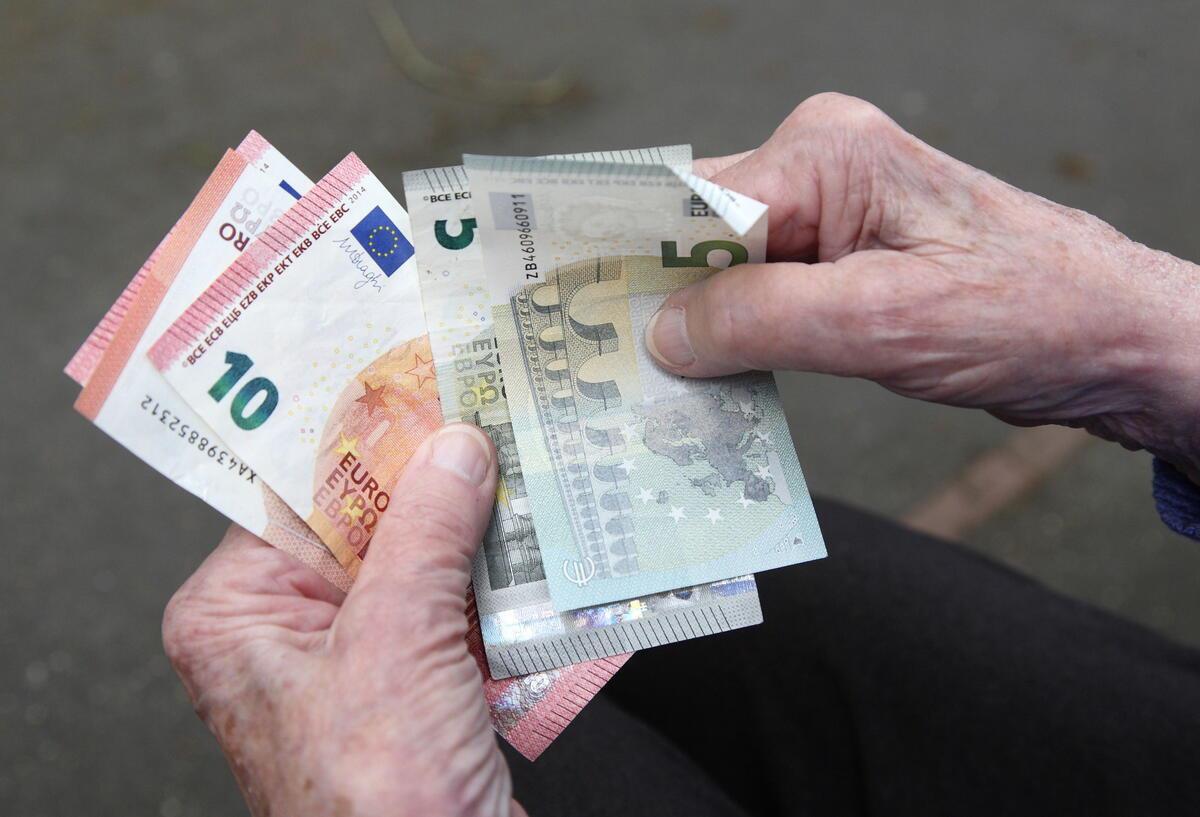 Eine Seniorin haelt Geldscheine in ihrer Hand.