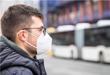Mann mit FFP2-Maske vor einem Bus.