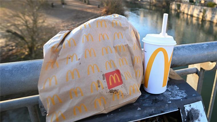 Eine McDonald's To-Go-Tüte und ein To-Go-Becher stehen auf einem Mülleimer auf der Neckarbrücke in Tübingen (gestellte Szene).