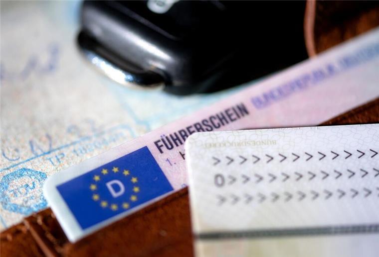 Ein Führerschein, ein Autoschlüssel, ein Personalausweis und eine Zulassungsbescheinigung liegen auf einem Portemonnaie