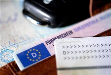 Ein Führerschein, ein Autoschlüssel, ein Personalausweis und eine Zulassungsbescheinigung liegen auf einem Portemonnaie