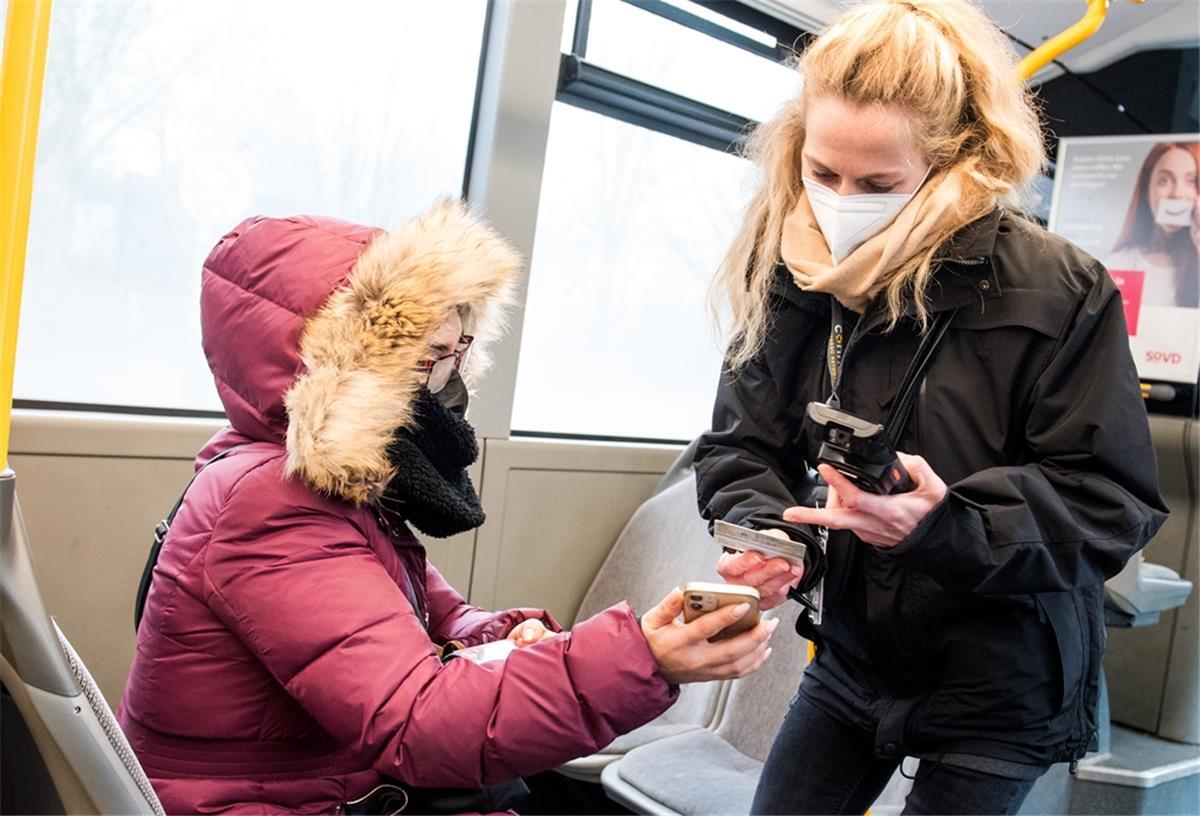 Eine Prüfdienst-Mitarbeiterin der Verkehrsbetriebe Hamburg-Holstein (VHH) kontrolliert in einem Bus den 3-G-Nachweis einer Passagierin.