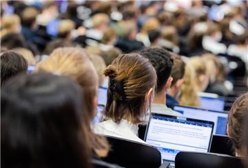 Studentinnen und Studenten sitzen während einer Vorlesung in einem Hörsaal.  Wer neben dem Studium arbeitet, muss auf Arbeitszeit, Einkommen und Versicherungen achten.