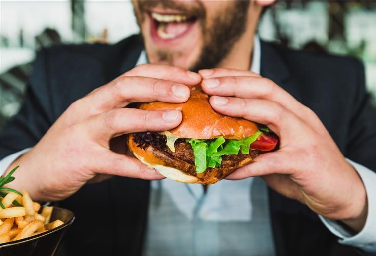 Ein Mann isst einen Burger.