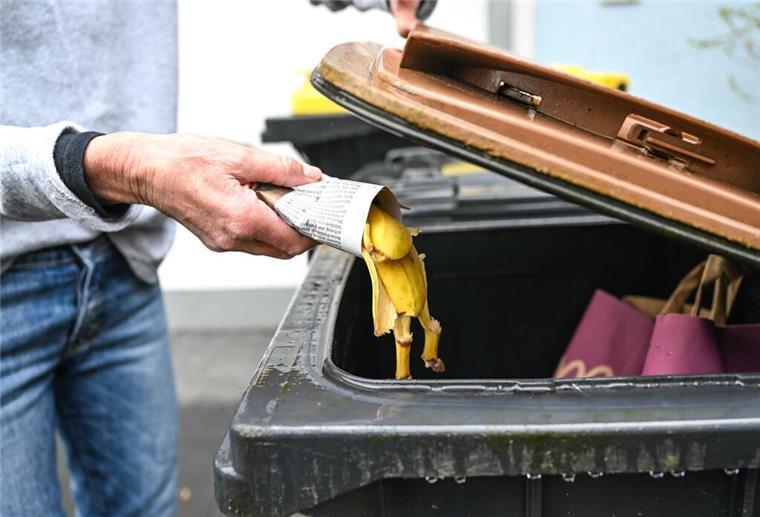 Bis zu 25.000 Euro Bußgeld! Diese wichtige Müll-Regel sollten alle Bürger kennen Eine Frau wirft in Zeitungspapier gewickelte Bananenschalen in eine Mülltonne für den Biomüll. Wer sich nicht an die Entsorgungsregeln für Müll hält, riskiert saftige Bußgelder. Diese können bis 25.000 Euro hoch sein.