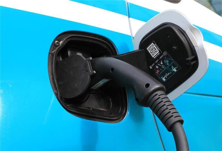 Ein Ladekabel steckt an einem Elektroauto,vor einer Ladesäule für E-Autos. Wer viel Strom verbraucht, beispielsweise durch den Besitz eines E-Autos, der kann mit dynamischen Stromtarifen viel Geld sparen.
