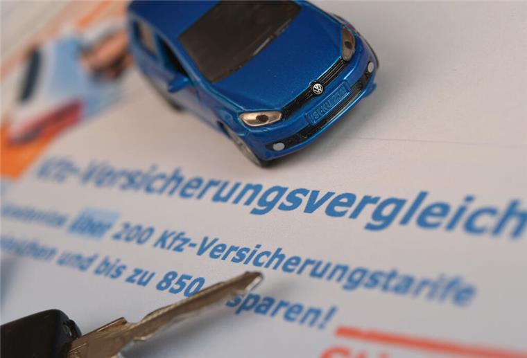 Wer Fahrer und Kilometer anpasst, spart bis zu 60% bei der Kfz-Versicherung Ein Miniaturauto und ein Autoschlüssel liegen auf einem Ausdruck.
