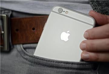 Eine Frau steckt sich ein iPhone der Firma Apple in die Hosentasche.