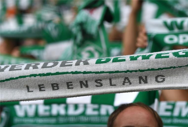 Werder Fans halten ihre Schals hoch. Darauf steht "Werder bewegt - Lebenslang". 