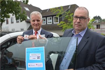 Wespa-Generalbevollmächtigter Bernd Meenzen (links) hält den Aufkleber für die Windschutzscheibe, Bürgermeister Thorsten Krüger die Plastikkarte mit dem Notfall-QR – beides kann im Ernstfall helfen, den Rettern schnelle Informationen über den jeweils Verunglückten zu liefern.