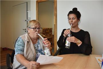 Wie ein Schlauch das Leben verändert: Schlaganfallpatientin Uta Wrage (links) kann dank der Lax-Vox-Methode wieder richtig sprechen. Dabei blubbert sie über einen Schlauch Worte, Sätze und schwierige Zungenbrecher in eine mit etwas Wasser gefüllte Flasche. Sprechtherapeutin Lena Hauptmeier probiert es auch einmal aus.  