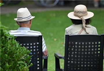 Ein Rentner-Ehepaar sitzt auf Stühlen im Garten.