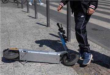 Passant steigt über einen abgelegten E-Scooter