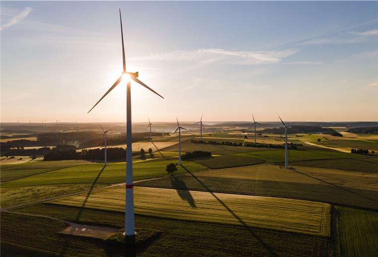 Windräder stehen während des Sonnenaufgangs auf einem Feld. Der Zubau der Windkraft an Land von Januar bis Ende September entwickelt sich.