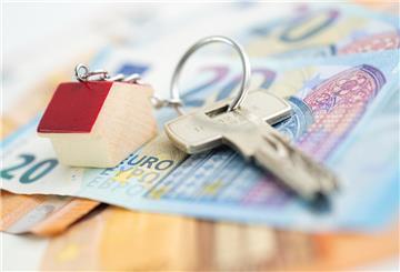 Auf einem Tisch liegt ein 20-Euro-Schein, auf dem ein Schlüssel mit Haus-Anhänger liegt.