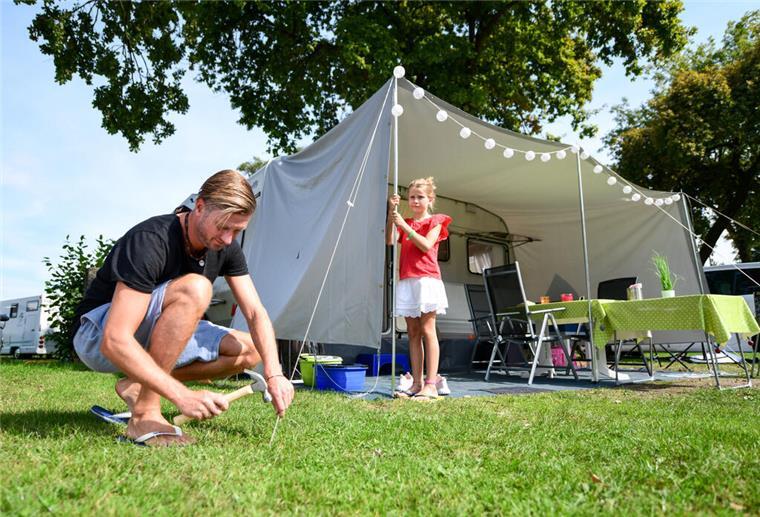 Camping im beliebten Urlaubsort: Diese Regeln müssen Wohnmobil-Reisende beachten Eine Familie baut ein Zelt auf.