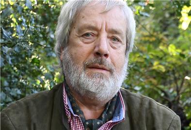 Wolfsberater Hermann Kück will Ende November aufhören. Mann mit Bart vor einer Hecke