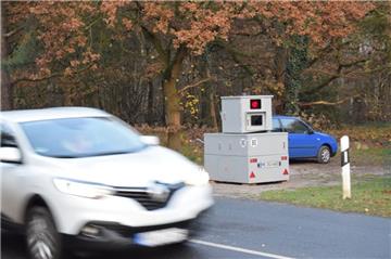 Auto auf Straße, dahinter grauer Kasten