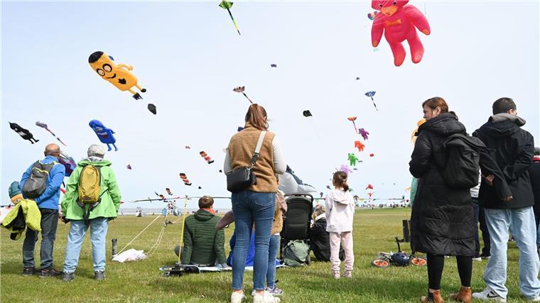 Bunte Drachen schweben am Himmel über Norddeich Zahlreiche Besucher beobachten die Choreografien der Drachensportler beim Drachenfest am Meer.