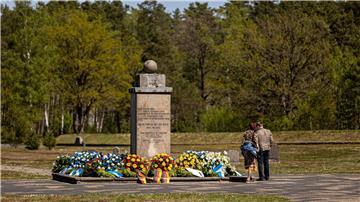 Zahlreiche Blumenkränze liegen um einen Gedenkstein auf dem Gelände der Gedenkstätte Bergen-Belsen.