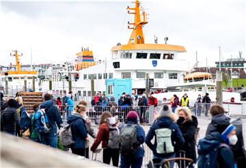 Zahlreiche Touristen warten im Fährhafen vor der Überfahrt zur Insel Langeoog auf den Zugang zum Fährschiff. 