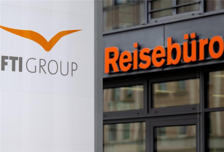 Das Logo des Reiseveranstalter FTI (FTI Group) steht an der Firmenzentrale vor einem Reisebüro.
