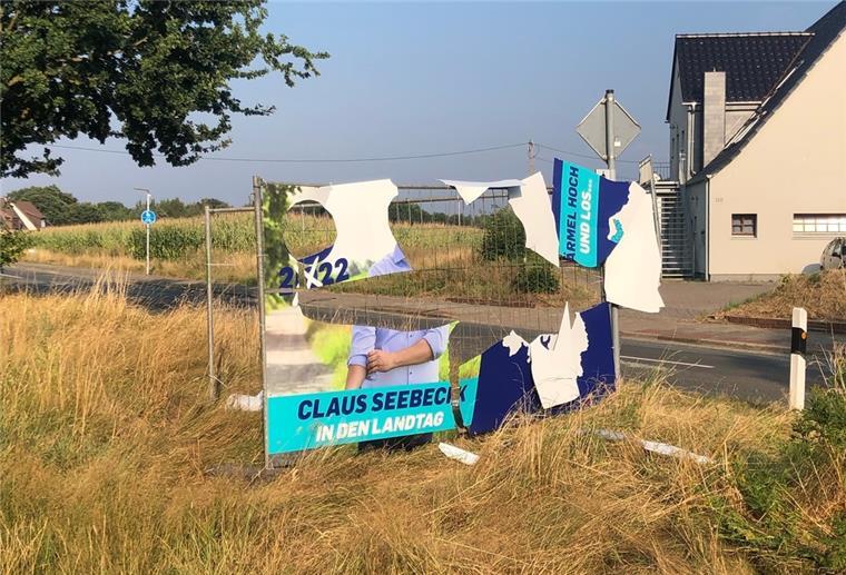 Ein abgerissenes Plakat an einem Bauzaun an einer Straße.