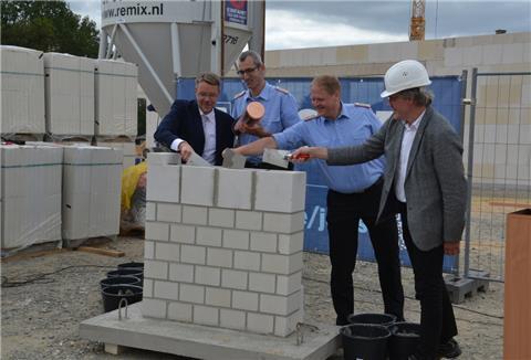 Zevens Ortsbrandmeister Jan Tobias Wendelken (Zweiter von rechts) mauert gemeinsam mit Samtgemeindebürgermeister Henning Fricke (links), Gemeindebrandmeister Torben Wilshusen und Hauke Uphoff-Bartelds (rechts), dem Leiter der Bremer Niederlassung des Bauunternehmens August Prien die Zeitkapsel ein.