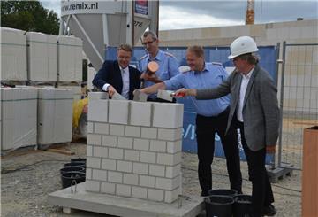 Zevens Ortsbrandmeister Jan Tobias Wendelken (Zweiter von rechts) mauert gemeinsam mit Samtgemeindebürgermeister Henning Fricke (links), Gemeindebrandmeister Torben Wilshusen und Hauke Uphoff-Bartelds (rechts), dem Leiter der Bremer Niederlassung des Bauunternehmens August Prien die Zeitkapsel ein.