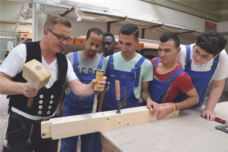 Zimmerermeister Jörn Krech zeigt Ibrahim Mohamedali Hassen, Abdusamad Abdoulmaula, Siamand Hassen, Schavgar Jendi und Mohamed Dolovan im Haus des Handwerks Zimmerertechniken. 