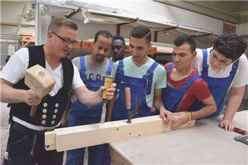 Zimmerermeister Jörn Krech zeigt Ibrahim Mohamedali Hassen, Abdusamad Abdoulmaula, Siamand Hassen, Schavgar Jendi und Mohamed Dolovan im Haus des Handwerks Zimmerertechniken. 